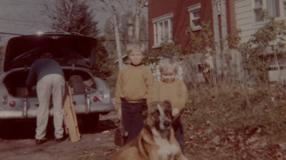 Carl Dow loads car as his sons and Dog stand in foreground